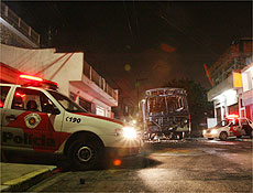 Policiais guardam nibus incendiado na zona leste de So Paulo, na noite de sbado (15)