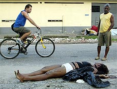 Pedestres observam o corpo de vtima da chacina no cho de uma rua de Nova Iguau