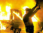 Policial passa ao lado de carro incendiado por rebelados