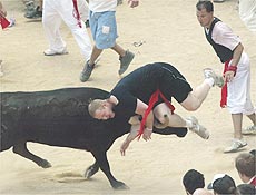 Homem  arremessado por touro durante corrida da festa de San Fermn, em Pamplona