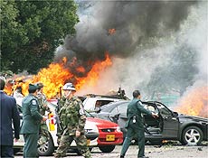 Militares checam carros em chamas aps exploso de bomba em universidade de Bogot