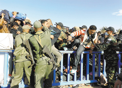 Soldados tunisianos auxiliam refugiados em Ras Jedir na fronteira do pas com a Lbia, onde milhares se concentram