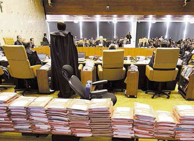 Autos do processo do mensalo, totalizando cerca de 50 mil pginas; o relator, ministro Joaquim Barbosa, de p, durante o primeiro dia do julgamento, no plenrio do Supremo