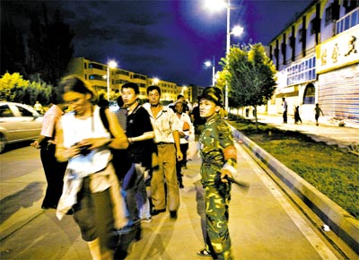 Soldado chins afasta jornalistas e curiosos do local do atentado, em Kashgar, na divisa com a ndia