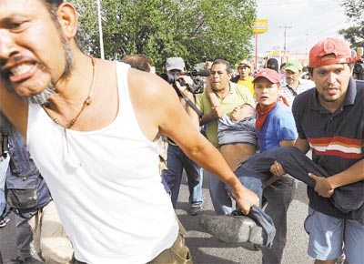 Apoiadores do presidente deposto carregam o corpo de homem<br>baleado e morto por soldados ontem no aeroporto de Tegucigalpa