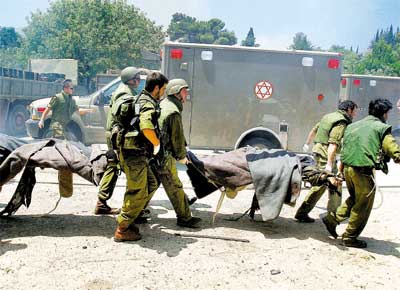 Em Kfar Giladi, no norte de Israel, soldados carregam corpos de colegas mortos por foguete lanado do Lbano pelo Hizbollah