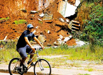 Ciclista passa por destroos de muro aps desabamento em Campos do Jordo (SP)