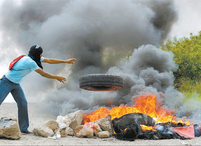 <b>FUTURO NEBULOSO:</b> Partidrio do presidente Manuel Zelaya, deposto em Honduras h 13 dias, queima pneus para bloquear estrada