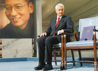 Thorbjoern Jagland, diretor do comit noruegus do Nobel, entrega simbolicamente Nobel da Paz ao dissidente Liu Xiaobo (foto ao fundo), impedido pela China de comparecer; ausncia  a primeira desde 1936