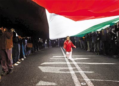Menina corre sob bandeira gigante palestina durante protesto no centro de Madri contra os ataques israelenses  faixa de Gaza
