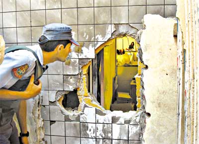 Policial observa o buraco aberto com uma bomba pelos ladres na empresa de valores Protege, na gua Branca, zona oeste de SP