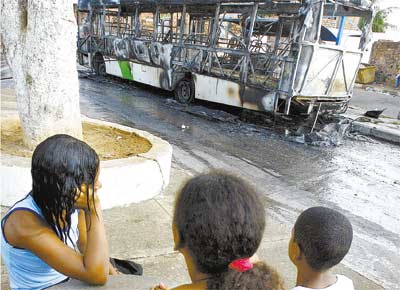 Crianas observam nibus incendiado no bairro de guas Claras, em Salvador; em cinco dias, dez suspeitos de participao em ataques a nibus e bases da PM morreram em confrontos