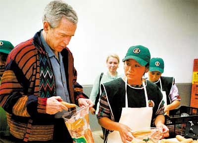 O presidente George W. Bush empacota cenouras em cooperativa de Chirijuy, na Guatemala