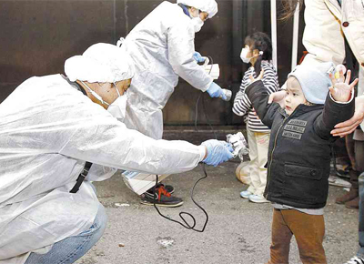 Com roupas especiais, funcionários do governo japonês checam sinais de radiação em crianças retiradas da região onde aconteceu vazamento nuclear