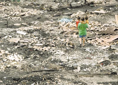 Moradora caminha com crianas entre escombros da favela Nova Jaguar, na zona oeste de So Paulo, aps incndio que destruiu cerca de 300 barracos e deixou mais de mil desabrigados anteontem