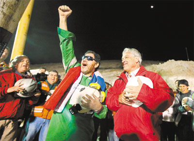 Luis Urza (de culos escuros), o ltimo mineiro a sair, festeja<br>o resgate ao lado do presidente chileno, Sebastin Piera