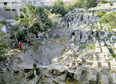 Palestinos se renem perto de cratera provocada por ataque da aviao<br>israelense ao cemitrio Sheik Radwan, na Cidade de Gaza