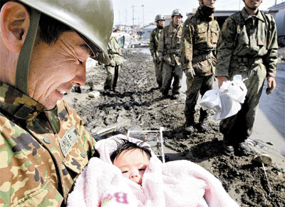 Membro de equipe de resgate carrega menina de 4 meses resgatada em Ishinomaki trs dias aps o tremor; o beb, j entregue ao pai, foi levado pela fora do tsunami dos braos da me, ainda desaparecida
