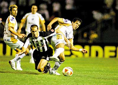Rodrigo Souto, do Santos, disputa bola com jogadores do Bragantino; partida terminou em 0 a 0, ontem  noite, no Pacaembu