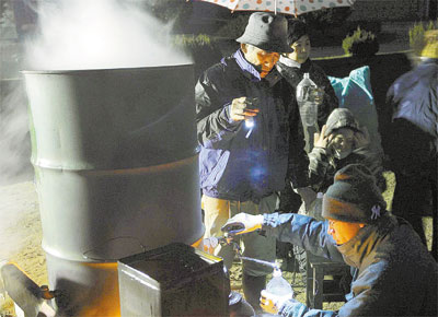 Sobreviventes do tsunami esquentam gua em abrigo em Kesennuma