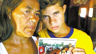 Andrelina, 53, e Robson, 13, mostram foto em que ela chorava a morte do marido, h 10 anos
