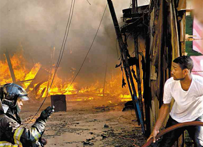 <b> FOGO:</b> Bombeiro e morador tentam apagar incndio na favela do Moinho, o 34 deste ano em SP