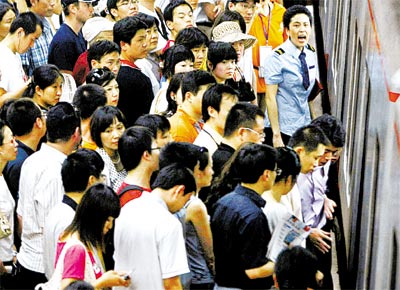 <b>Cena familiar:</b> Funcionria do metr de Pequim (de gravata) orienta passageiros em estao superlotada devido a rodzio de carros