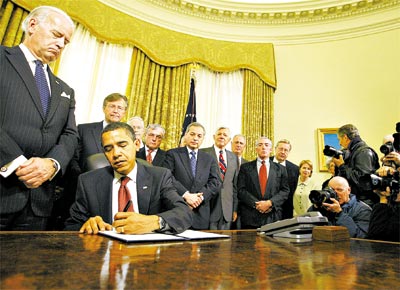 Observado pelo vice, Joe Biden ( esq.), e por oficiais da reserva,<br>o presidente Barack Obama assina ordens executivas