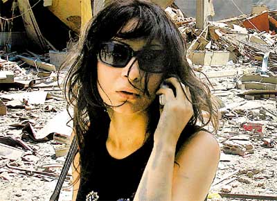 Mulher libanesa fala ao celular em rua de subrbio de Beirute destrudo por ataques de Israel
