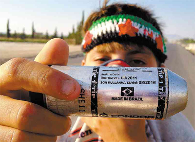 Menino srio segura bomba de gs lacrimogneo fabricada no Brasil, pela Condor, e disparada pela polcia turca em campo de refugiados na fronteira