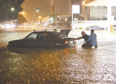 <b>FORA CONTRA AS GUAS:</b> Homens puxam carro na Braz Leme, avenida da zona norte paulistana; chuva isolou mais de cem pessoas