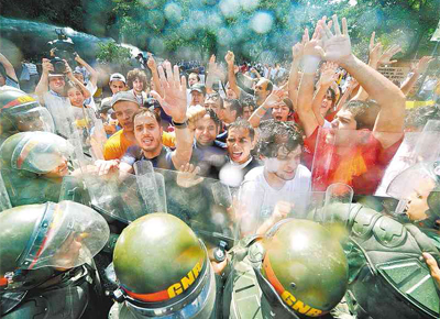 Sob jatos d'gua, estudantes protestam em frente  Universidade Central da Venezuela contra a lei do ensino superior