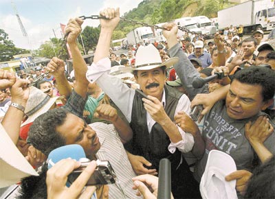 O presidente deposto de Honduras, Manuel Zelaya, ergue corrente <br>que assinala a divisa de Las Manos, na Nicargua, com seu pas