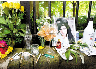 Taas de vinho, cigarros e flores colocados por fs no muro da casa de Amy, em Londres