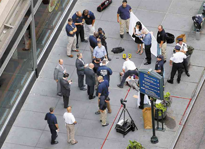 Integrante de equipe de emergncia inspeciona corpo do suspeito de ser o atirador diante do Empire State, em Nova York