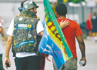 Usando capacete com bolinha de papel, militante tucano anda com petista no Rio, onde Dilma e Serra fizeram campanha