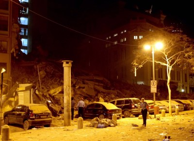 Escombros dos prédios que caíram, com as luzes do Theatro Municipal ao fundo; no detalhe, mulher que estava próxima ao local