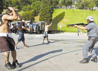 Policial militar mira torcedor corintiano em um dos tumultos ocorridos no jogo contra o Palmeiras, no Pacaembu