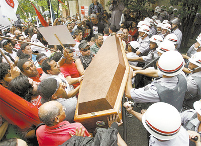 Manifestantes investem com caixo simbolizando a morte da educao contra cordo de PMs, em frente ao estdio do Morumbi