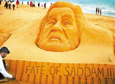 Artista indiano retoca escultura em areia do rosto de Saddam Hussein intitulada 