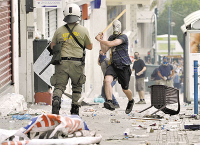 Em ato marcado pela violncia, mascarado ameaa policial em Atenas; greve geral de 48 h foi convocada e Parlamento deve iniciar hoje votao de pacote econmico com medidas austeras