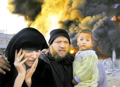Famlia palestina passa por prdio em chamas aps mssil<br>israelense ter acertado campo de refugiados de Rafah