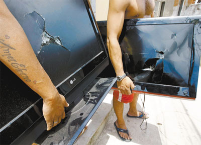Moradores do Alemo (zona norte) mostram TVs danificadas durante revista na favela