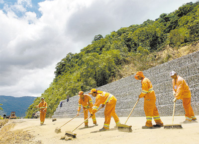 <b>REABERTURA EM MO NICA:</b> Diante de muro de conteno, funcionrios varrem a Mogi-Bertioga, rodovia de acesso ao litoral norte