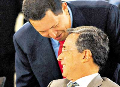 Os presidentes Hugo Chvez (de p) e lvaro Uribe conversam durante reunio do Grupo do Rio