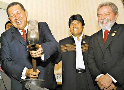 Chvez usa martelo para cunhar moeda comemorativa, acompanhado por Morales e Lula, que participam da reunio de cpula sul-americana em Cochabamba, na Bolvia