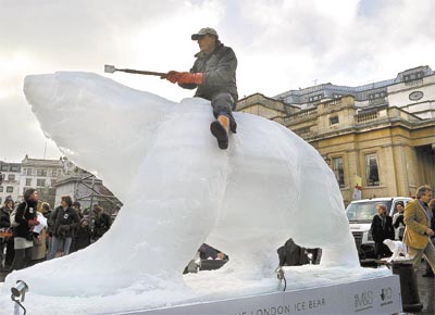 Escultor trabalha em urso polar de gelo, na Trafalgar Square, centro de Londres; instalação é parte de campanha contra o aquecimento global
