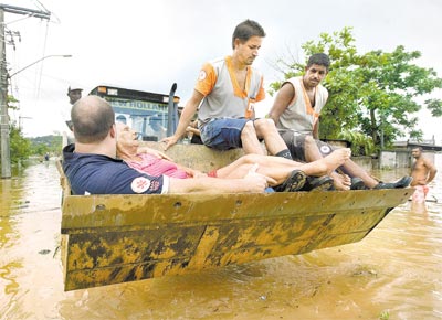 <b>SOBRE AS ÁGUAS:</b> Equipe de resgate usa escavadeira para<br>transportar moradora de Belford Roxo (Baixada Fluminense)