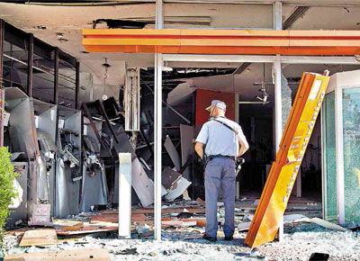 Policial militar observa agncia do banco Ita que teve seis caixas eletrnicos explodidos ontem, na capital