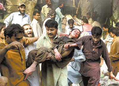 Homem carrega corpo de garoto morto depois de ataque a mercado<br>em Peshawar; vtimas foram, na maioria, mulheres e crianas